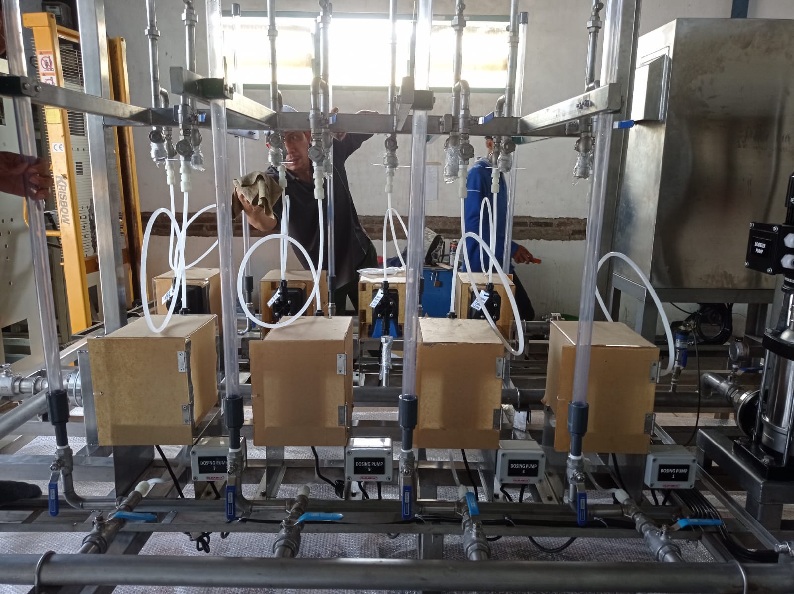Seorang teknisi sedang mengerjakan instalasi tubing pada salah satu jalur pompa dosing