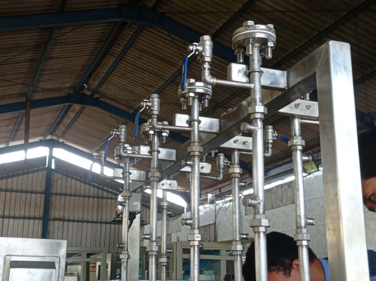 Detail close-up dari sistem perpipaan dan valve stainless steel di bagian atas skid