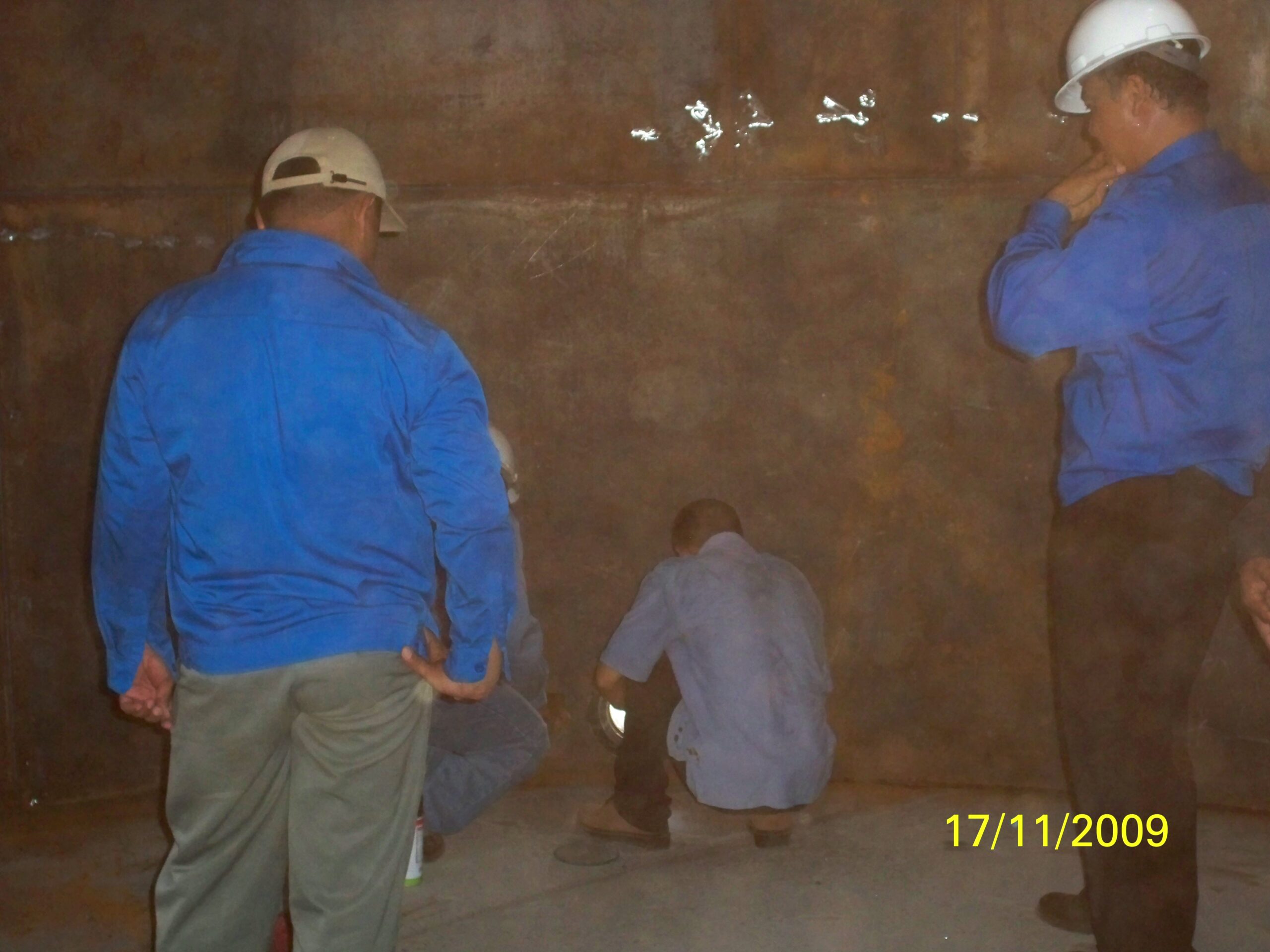 Tim inspeksi sedang memeriksa bagian dalam tangki bahan bakar yang sedang dalam tahap konstruksi.