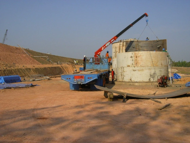 Mobile crane menurunkan pelat lantai tangki yang telah difabrikasi.