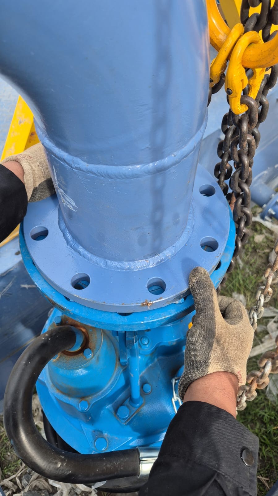 Proses pengecekan akhir kesejajaran lubang baut flange antara pipa discharge dan nozzle pompa submersible.