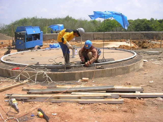 Teknisi melakukan pengukuran dimensi pada pelat baja sebelum proses fabrikasi.