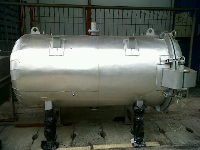 Sebuah retort horizontal stainless steel di atas penyangga sementara di dalam workshop