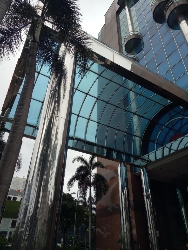Detail kolom stainless steel dan atap kaca lengkung pada fasad gedung yang menjadi inspirasi desain kanopi.