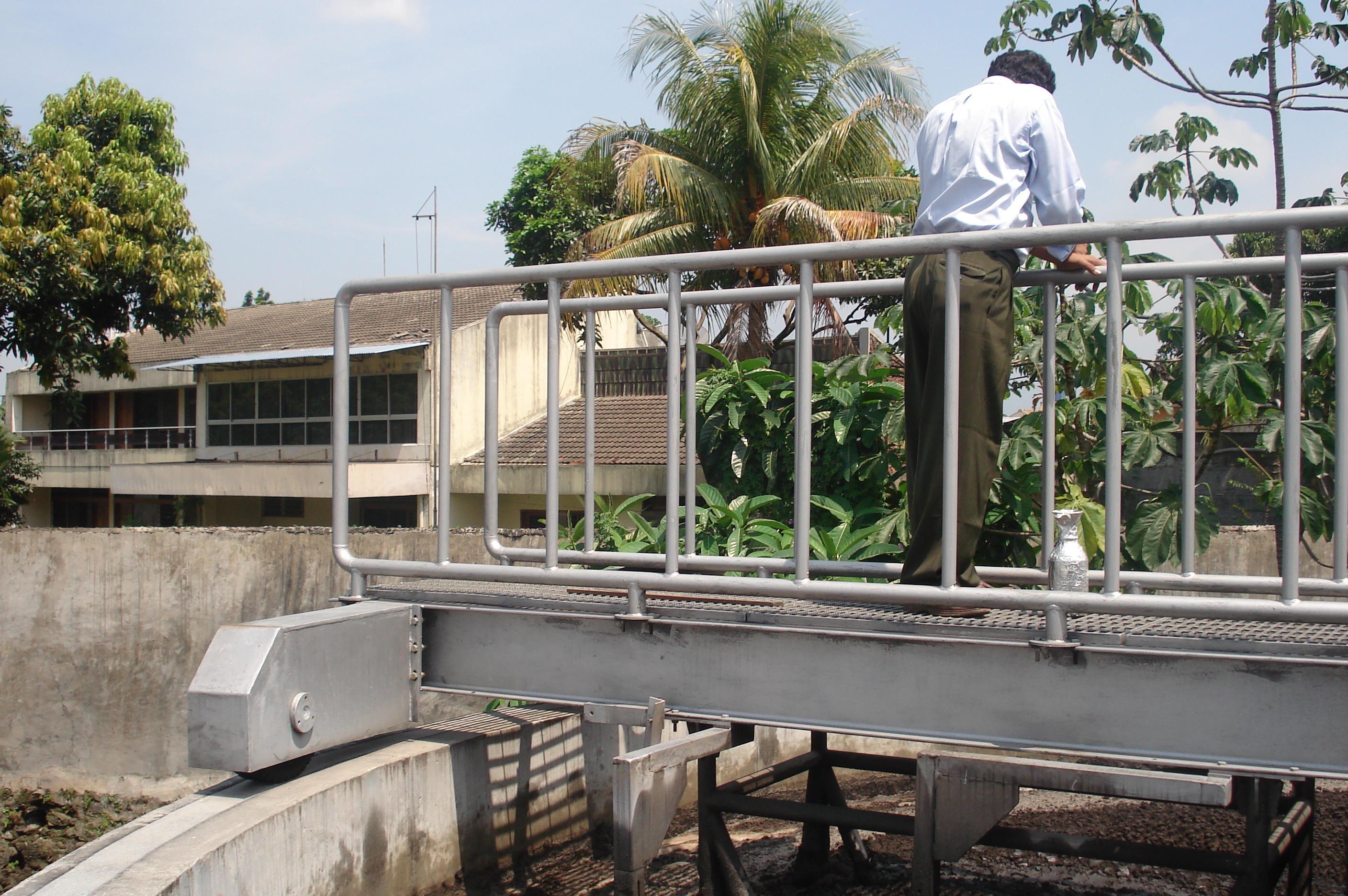 Seorang teknisi melakukan inspeksi di atas jembatan putar tangki clarifier.